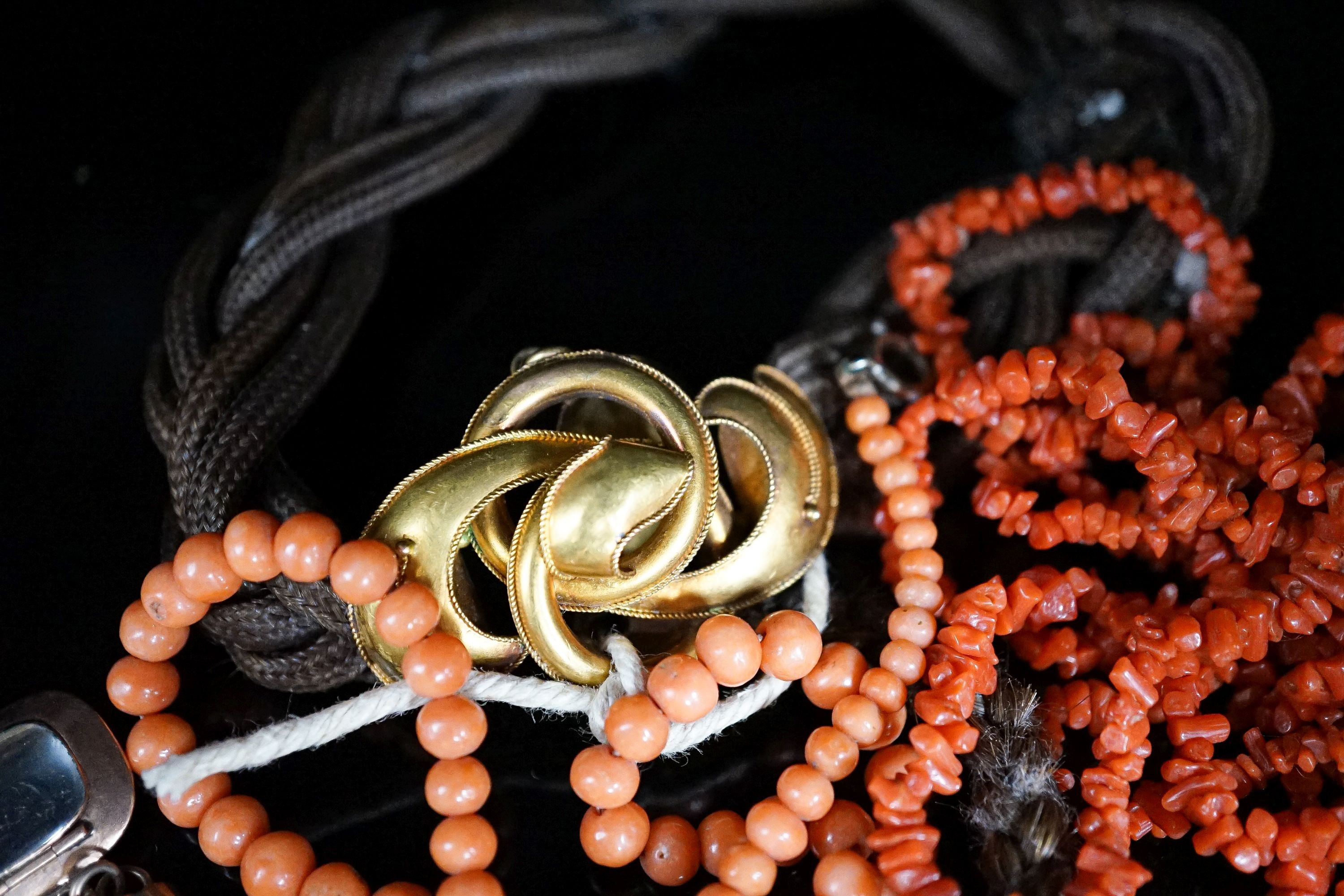 A Victorian yellow metal mounted hairwork bracelet, hung with plaited hair tassel with yellow metal fob, and two coral necklaces.